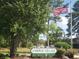 The image shows the 'Fairway Village' sign with a waving American flag among green foliage at 500 Fairway Village Dr. # 9-K, Myrtle Beach, SC 29588