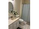 The bathroom has a round mirror, white vanity, toilet, and a shower/tub with a striped curtain at 5001 Little River Rd. # W101, Myrtle Beach, SC 29577