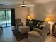 A furnished living room includes a sliding glass door, a sofa, two chairs, and an ottoman at 5001 Little River Rd. # W101, Myrtle Beach, SC 29577