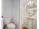 Powder room featuring a pedestal sink, round mirror with lights, and a white toilet at 1120 Fairway Ln. # 1120, Conway, SC 29526
