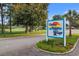 Community sign reads Timber Ridge Village with colorful tree art, surrounded by lush landscaping and green grass at 1145 Forest Dr., North Myrtle Beach, SC 29582