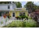 Charming yellow home featuring a white picket fence, lush garden, and vibrant flowers, creating a welcoming curb appeal at 12 Century St. # 12, Myrtle Beach, SC 29577