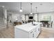 Open-concept kitchen featuring a large island with seating, stainless steel appliances, and views of the living and dining areas at 1408 Whistling Straits Way, Sunset Beach, NC 28468