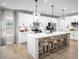 Modern kitchen with white cabinets, stainless steel appliances, an island with barstool seating and pendant lights at 1408 Whistling Straits Way, Sunset Beach, NC 28468