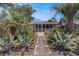 Charming home featuring a landscaped front yard with a tiled pathway surrounded by palm trees and greenery at 1416 Edge Dr., North Myrtle Beach, SC 29582