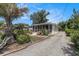 Exterior view of home with a gravel driveway and front yard featuring tropical plants leading to a screened-in porch at 1416 Edge Dr., North Myrtle Beach, SC 29582