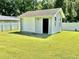 A light gray storage shed in the backyard with a roll-up door on a large grassy lawn at 1421 Shoreline Dr., Myrtle Beach, SC 29577