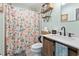 Bathroom with floral shower curtain, sink with modern fixtures, and open storage shelves at 169 Ole Maple St., Loris, SC 29569