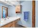 Bathroom with wooden vanity, framed mirror, storage cabinet, and a blue towel at 201 Surrey Ln., Myrtle Beach, SC 29579