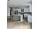 Bright kitchen with white cabinets, stainless steel appliances, a gray island, wood floors, and pendant lights at 2075 Lees Landing Circle, Conway, SC 29526