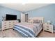 Bright bedroom with light blue walls and wood-look flooring featuring a bed, TV, and dressers at 2885 Desert Rose St., Little River, SC 29566