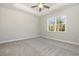 Bright bedroom featuring a tray ceiling, fan, neutral carpet, and a large window providing ample natural light at 369 Log Cabin Rd., Loris, SC 29569