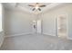 Spacious main bedroom featuring neutral carpeting, a tray ceiling with fan, and doorways leading to the bathroom and kitchen at 369 Log Cabin Rd., Loris, SC 29569