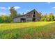 Rustic barn on a sprawling property, surrounded by lush greenery and open fields, showcasing the property's charm at 3930 West Marion St., Mullins, SC 29574
