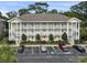 Three-story condo building with white railings, stairs, parking, and landscaping at 4261 Hibiscus Dr. # 4-104, Little River, SC 29566