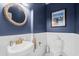 Charming powder room with navy blue walls, white wainscoting, oval mirror and bronze fixtures at 5 Ruth St., Murrells Inlet, SC 29576