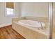 Luxurious bathroom with an oval soaking tub, tile surround, and hardwood floors at 55 Pineberry Dr., Georgetown, SC 29440