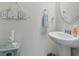 Charming powder room featuring a pedestal sink, round mirror, and beach-themed decor at 668 Rycola Circle, Surfside Beach, SC 29575