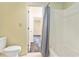Clean bathroom showcasing a toilet, bathtub with shower curtain, and a doorway leading to other rooms at 6703 Jefferson Pl. # G5, Myrtle Beach, SC 29572
