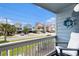A cozy balcony with seating offers a neighborhood view of charming beach houses and lush greenery at 1210 N Ocean Blvd. # 104, Surfside Beach, SC 29575