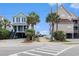 Charming street view of raised beach houses with palm trees, leading to a sandy beach access point at 1210 N Ocean Blvd. # 104, Surfside Beach, SC 29575