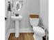 A well-lit powder room features a pedestal sink, round mirror, and wood-look floors at 1216 Newell Dr, Myrtle Beach, SC 29588