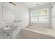 Light bathroom with a tub, window, and a sink with gold hardware at 149 Old Cedar Loop, Pawleys Island, SC 29585