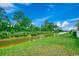 Manicured backyard with a river view, a grassy slope, and a line of trees in the background at 153 Goldenrod Circle # 7D, Little River, SC 29566