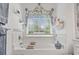 Bright bathroom features a tub with a view, floral valances, and open shelving for storage at 185 Rocko Dr., Myrtle Beach, SC 29579