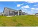 View of the home's backyard featuring a spacious lawn area, screened porch, and the home's gray siding at 1898 Moonseed Dr., Longs, SC 29568