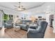 Open-concept living room with wood floors, tray ceiling, ceiling fan, and comfortable seating with access to backyard at 1898 Moonseed Dr., Longs, SC 29568