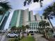 Exterior view of the high-rise Sandy Beach Oceanfront building with palm trees at 201 S Ocean Blvd. # 205, Myrtle Beach, SC 29577