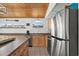 Kitchen area with wood ceiling, stainless refrigerator, stove and sink under windows that provide natural light at 204 55Th Ave. N, North Myrtle Beach, SC 29582