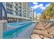 Resort pool with lounge chairs, palm trees, and hotel condos on a sunny day at 2300 N Ocean Blvd. # 132, Myrtle Beach, SC 29577