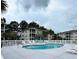 Community pool surrounded by a white fence, lounge chairs, palm trees, and low-rise apartment buildings at 2498 Coastline Ct. # 301, Murrells Inlet, SC 29576