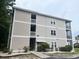 View of condo exterior featuring a multi-story building, green landscaping, and a labeled entrance at 2498 Coastline Ct. # 301, Murrells Inlet, SC 29576