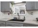 Kitchen sink area featuring gray cabinetry and backyard views through a window at 2738 Canvasback Trail, Myrtle Beach, SC 29588