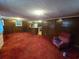 Open living room with a chair, red carpet, wood-paneled walls, and a small kitchen counter at 331 Dixon St., Mullins, SC 29574