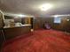 Open living room featuring red carpet, wood-paneled walls, and a small kitchen counter at 331 Dixon St., Mullins, SC 29574
