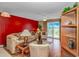 Living room with red accent wall, balcony access, and comfortable, neutral-toned furniture at 4366 Rivergate Ln. # 306, Little River, SC 29566