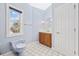 A cozy bathroom with a window, oak vanity, and unique light purple toilet at 4552 River Rd., Little River, SC 29566