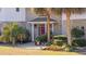 Home's entrance with brickwork, pillars, red door, and a neatly landscaped yard with palms at 4552 River Rd., Little River, SC 29566
