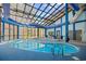An indoor pool with a glass ceiling, tables and chairs next to the pool at 4800 S Ocean Blvd. # 514, North Myrtle Beach, SC 29582