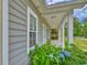 Cozy front porch with classic columns, wood-look swing, and verdant blue hydrangeas at 4867 Wolf Trail, Conway, SC 29527