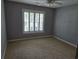 This bedroom features a neutral carpet, a large window with shuttered blinds, light gray walls, and a ceiling fan at 6542 Wellington Dr., Murrells Inlet, SC 29576