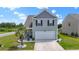 Charming two-story home featuring light gray siding, a two-car garage, and a neatly landscaped front yard with a small palm tree at 798 Woodland Farms Circle, Aynor, SC 29511