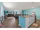 Open-concept living area with modern turquoise walls, dark wood floors, a kitchen island, and comfortable leather seating at 798 Woodland Farms Circle, Aynor, SC 29511