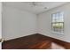 An empty bedroom featuring hardwood floors, a ceiling fan, and a window with outside views, offering ample space at 964 Great Egret Circle Sw # B, Sunset Beach, NC 28468
