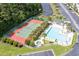 Aerial view of a community pool and tennis courts surrounded by lush greenery and palm trees at 964 Great Egret Circle Sw # B, Sunset Beach, NC 28468