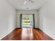 A bright, minimalist living room with hardwood floors provides access to a balcony with outdoor views at 964 Great Egret Circle Sw # B, Sunset Beach, NC 28468